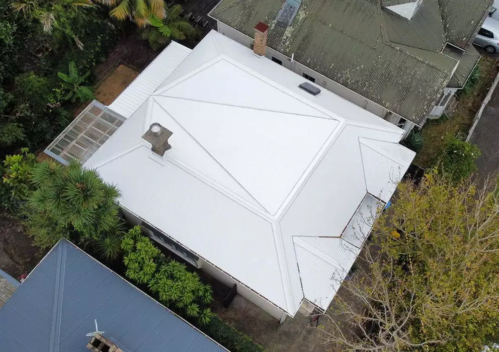 A white long run roof on a residential villa home with existing chimney.